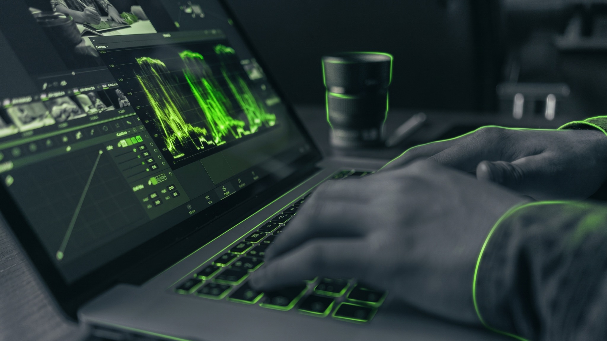 Creative professional colour grading footage on a laptop with lime-lit editing scopes