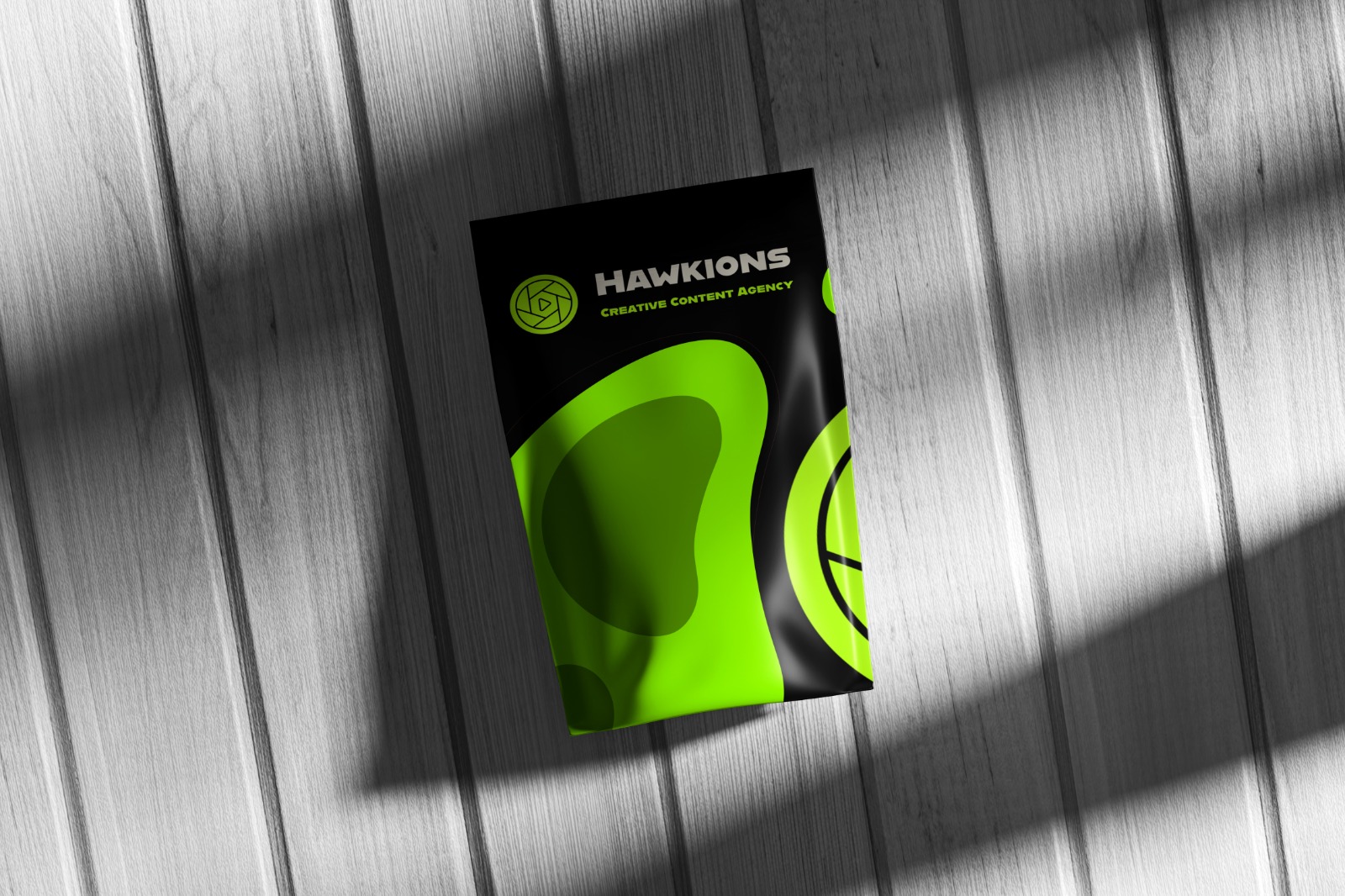 Hawkions black and lime printed brand collateral on a wood surface